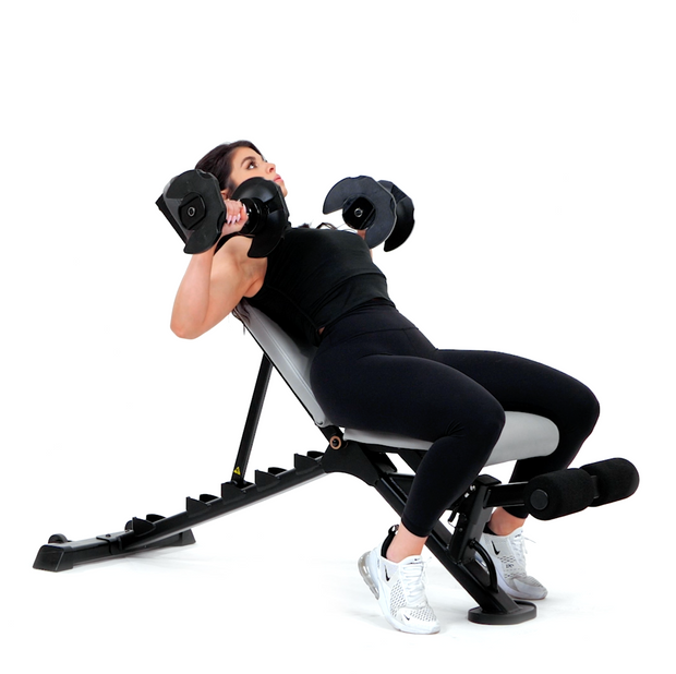 Angled View of Woman Doing Chest Press with Adjustable Dumbbells Laying on Glute Drive Plus